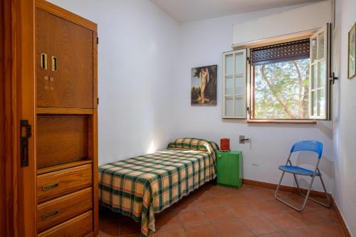 ein kleines Schlafzimmer mit einem Bett und einem Stuhl in der Unterkunft Villa degli Ulivi in San Pietro in Bevagna