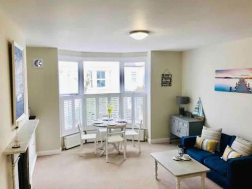 a living room with a table and a blue couch at St Margarets Modern Georgian 2 bedroom apartment in Ryde