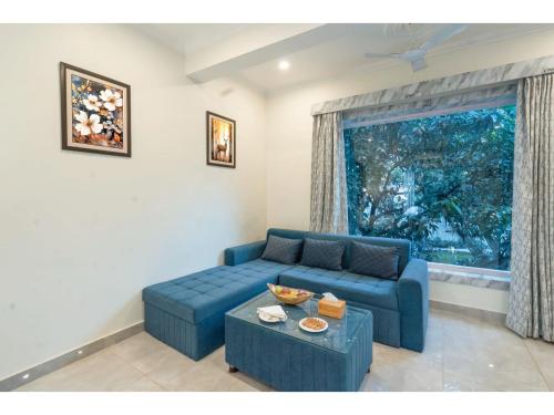 een blauwe bank in een woonkamer met een raam bij River Heritage Resort in Dhikuli