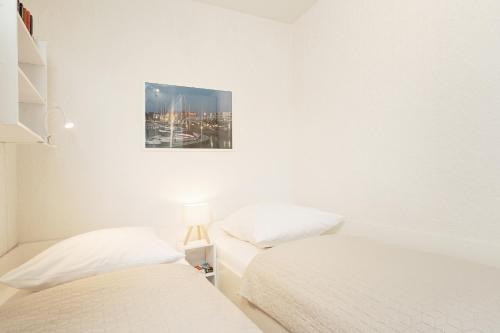 two beds in a white room with a picture on the wall at Stranddistel 4 Deck 2 in Fehmarn