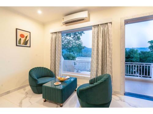 een woonkamer met twee stoelen, een tafel en een raam bij River Heritage Resort in Dhikuli