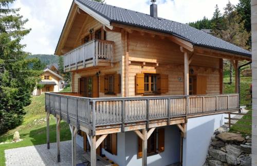 a log cabin with a deck and a house at Almrausch-Feriendorf Koralpe in Elsenbrunn