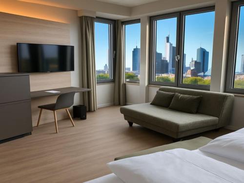 オッフェンバッハにあるEast Five Hotelのベッド、ソファ、デスクが備わるホテルルームです。