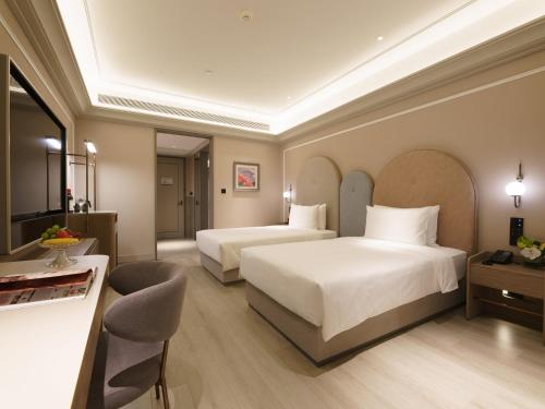 a hotel room with two beds and a table at Mercure Xi'an Stadium Hotel in Xi'an