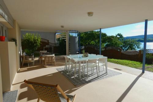a patio with a white table and chairs on a balcony at LAC CASA 60' Sixties-style flat with terrace overlooking the lake 300 m in Bilieu