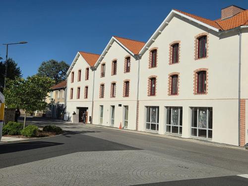 a white building with red windows on a street at Hotel Rivella - The Originals Boutique in Clisson