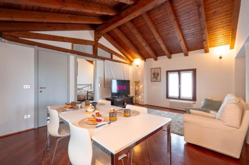 ein Wohnzimmer mit einem weißen Tisch und Stühlen in der Unterkunft Centralissimo vista Municipio, Elegante con Rooftop in Pordenone