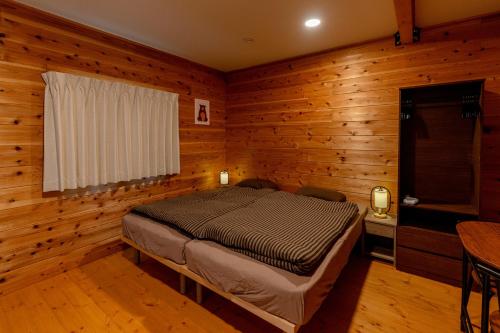 een slaapkamer met een bed in een kamer met houten wanden bij Azumino Bear's Inn in Azumino