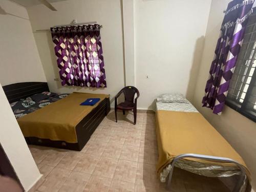 a room with two beds and a chair in it at Rivera Homestay in Udupi