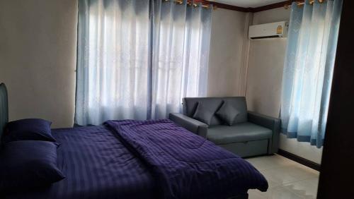 a bedroom with a bed and a chair and a window at Supunpong Pool Villa in Nakhon Nayok