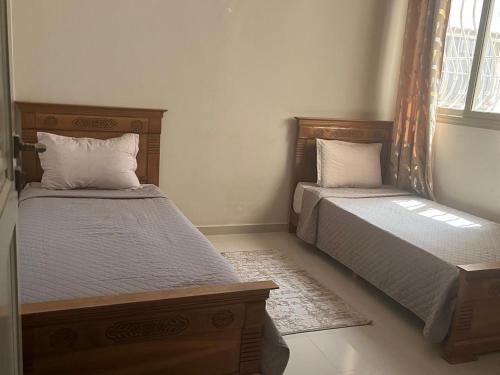 a bedroom with two beds and a window at avenue hassan 2 agadir in Oulad Akkou