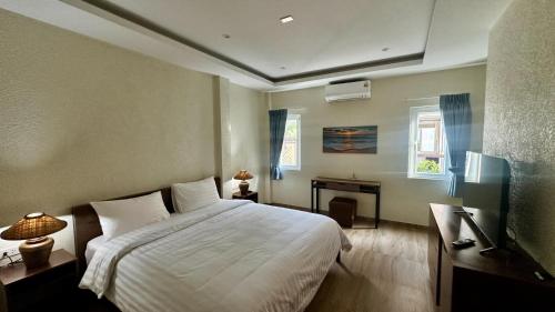 Schlafzimmer mit einem weißen Bett, einem Schreibtisch und einem Fenster in der Unterkunft Villa Bella Serene 5E in Ban Khlong Son
