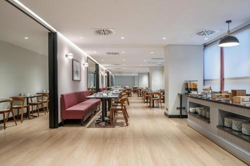 マドリードにあるEurostars Puerta Madridのバーとテーブルと椅子のあるレストラン