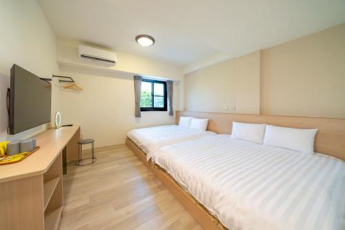 une chambre avec un grand lit blanc et un bureau dans l'établissement 橙居 台南安平包棟民宿 依人數開放房型 麻將 唱歌 泡湯屋 加大雙人床, à Anping