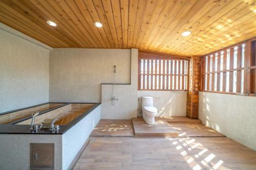 La salle de bains est pourvue de toilettes et d'un plafond en bois. dans l'établissement 橙居 台南安平包棟民宿 依人數開放房型 麻將 唱歌 泡湯屋 加大雙人床, à Anping