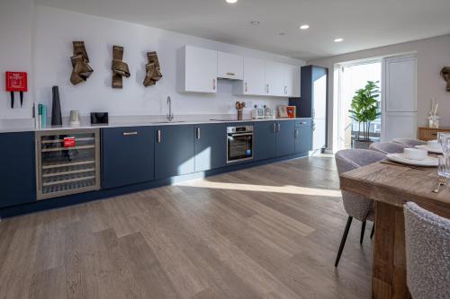 a kitchen with blue cabinets and a wooden floor at BRAND NEW! Modern & Spacious Serviced Apartments With FREE Parking & Gym by Rapid Returns - Professional Host in Walton-on-Thames