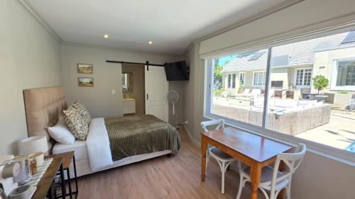 a bedroom with a bed and a table and a window at Camellia Cottage - Pool Room in Constantia