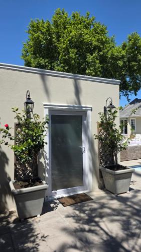 two potted plants sitting in front of a garage at Camellia Cottage - Pool Room in Constantia