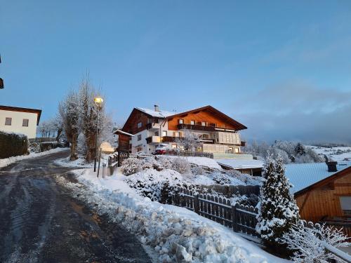 a snow covered street with a house in the background at Residence Rastbichl - Apartments & Indoor-Pool in Maranza