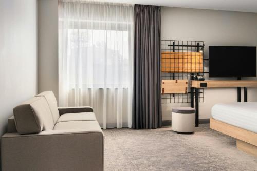 a bedroom with a bed and a couch and a tv at Moxy Belfast City in Belfast
