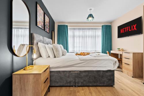 a bedroom with a large bed and a mirror at Stylish & Spacious 3BR 3Bath with Private Parking, WiFi, Smart TVs in Spon End