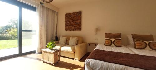 a bedroom with a bed and a couch and a window at B&B 't Goedhof in Maaseik
