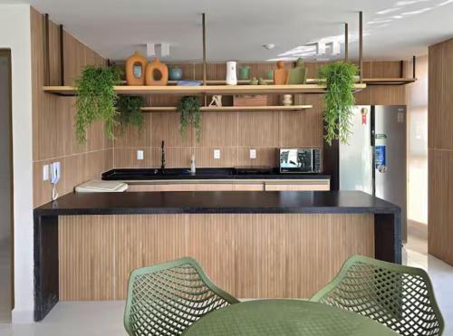 a kitchen with a counter with two green chairs at Flat com vista linda para o mar! in Cabedelo