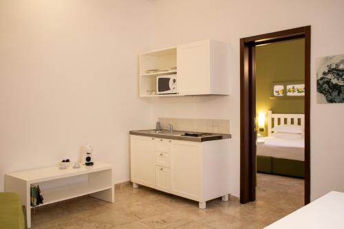 a kitchen with a sink and a room with a bed at San Domenico Residence by BADIA NUOVA in Trapani