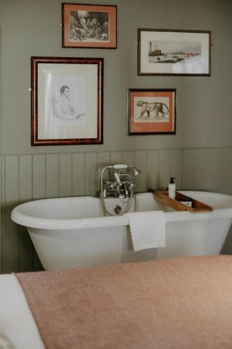 a bath tub in a room with pictures on the wall at The Bull And Swan in Stamford