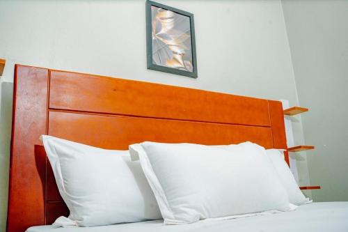 a bed with a wooden headboard and two white pillows at BougainVille in Fort Portal