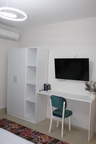 einen weißen Schreibtisch mit Stuhl und einen TV an der Wand in der Unterkunft Nestly Rooms in Sauk