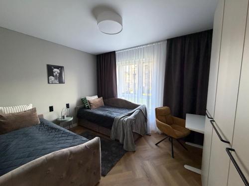 a bedroom with a bed and a chair and a window at Two bedroom LUXURIOUS Spacios Apartment in Vilnius
