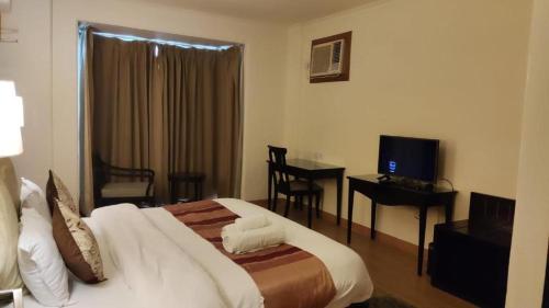 a bedroom with a bed and a desk and a television at Aloha 1 & 2 BHK with Infinity Pool in Rishīkesh