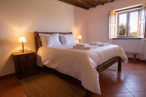 a bedroom with a bed with white sheets and a window at Horta dos Caracóis in Borba