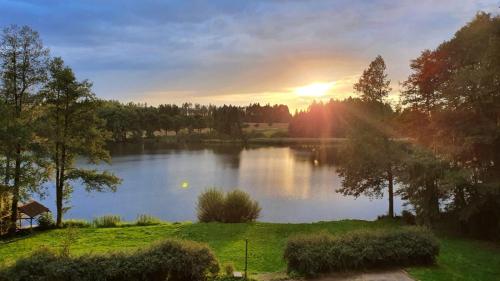 a view of a lake with the sun setting at Hotel Chytrov in Volfířov