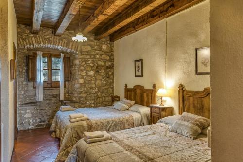 a bedroom with two beds and a stone wall at La Torre de Dalt in Santa María de Camós