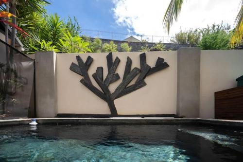 a tree stenciled on a wall next to a swimming pool at COTTAGE BAMBOU classé 3 étoiles - 4 à 6 personnes - 2 chambres - avec piscine privée et accès direct à la plage et à l'esplanade de Boucan Canot avec ses bars et restaurants in Saint-Gilles les Bains