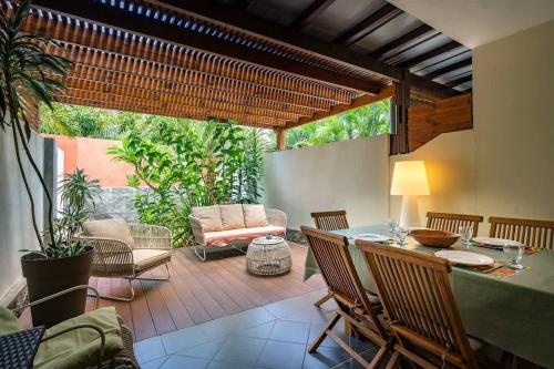a patio with a table and chairs and a couch at COTTAGE BAMBOU classé 3 étoiles - 4 à 6 personnes - 2 chambres - avec piscine privée et accès direct à la plage et à l'esplanade de Boucan Canot avec ses bars et restaurants in Saint-Gilles les Bains