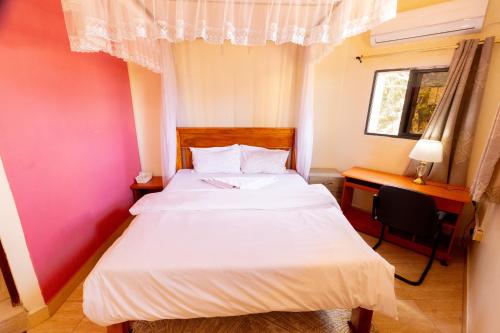 a bedroom with a bed and a desk and a window at Jade Inn in Arusha