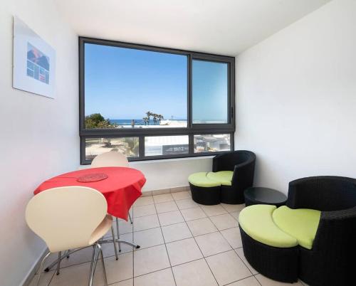 a living room with a table and chairs and a window at ROYCE classé 3 étoiles - Appartement 4 personnes - Vue mer - idéalement situé sur le front de mer et à 200 m du lagon de ST-PIERRE in Saint-Pierre