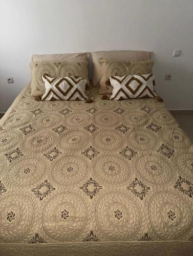 a bed with a comforter and pillows on it at L Escale de l Atlantique Dar Salma fibre optique piscines,clim&parking in Tangier