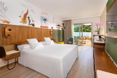 a bedroom with a large white bed and a living room at Adrián Hoteles Jardines de Nivaria in Adeje