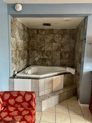 a bath tub in a bathroom with a red chair at Skylark Motel in Chicago