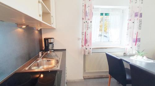 a kitchen with a sink and a table and a window at Ferienwohnungen Trattler in Chieming