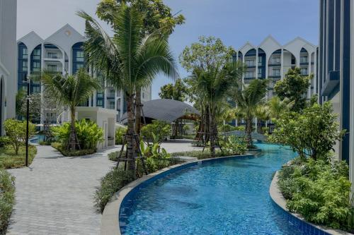 a pool with palm trees in front of a building at Modern 1 & 2 Bedroom Apartments Naiyang Phuket by Mango Family in Nai Yang Beach