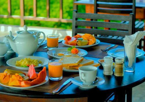 une table avec des assiettes de nourriture et une théière dans l'établissement Sunglow Safari Resort, à Uda Walawe