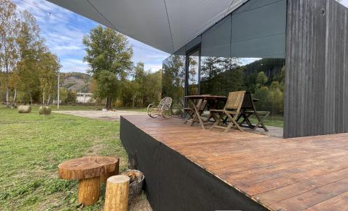 a wooden deck with a table and chairs on a field at Quiet Anomaly Glamping Forest & Wellness Retreat Adults Only in Pirkenhammer