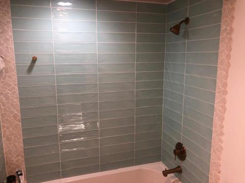 ein Bad mit einer Badewanne und einer Dusche mit blauen Fliesen in der Unterkunft Canal Front 3 bedroom 2 bathroom in Nassau