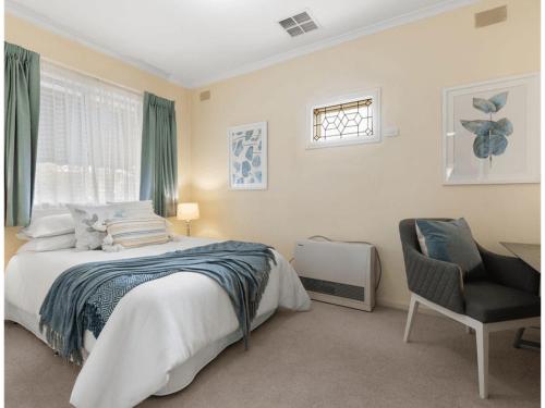 a bedroom with a bed and a chair and a window at 3BR Guest House near Adelaide CBD Joslin 5070 in Evandale