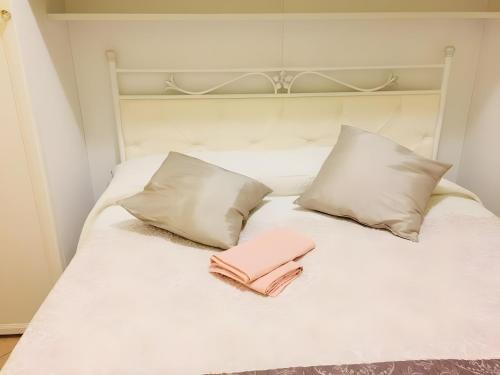 Una cama blanca con 2 almohadas y una toalla rosa. en Rosato 14-balcone Sul Mare, en Stazione Marittima